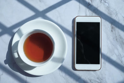 Top view of smart phone and tea on table at morning