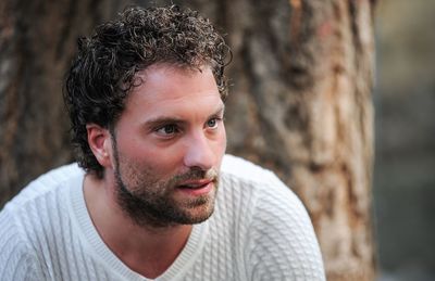 Close-up of thoughtful mid adult man sitting against tree