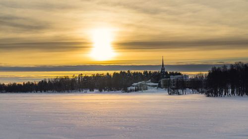 Scenic view of snow covered landscape against sky during sunset