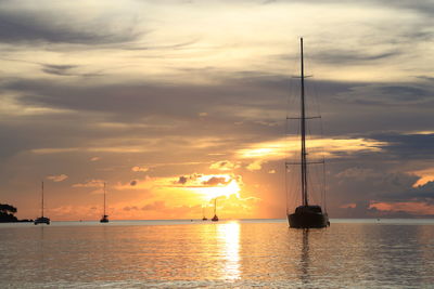 Sailboats in sea against sky during sunset