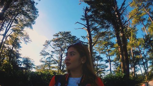 Low angle view of woman against trees against sky