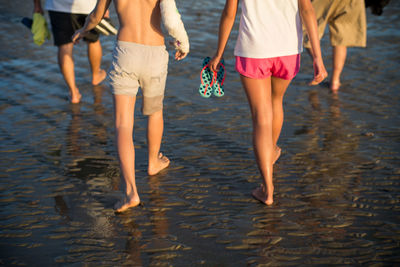 Low section of women walking on beach