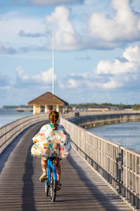 Middle aged woman riding a bicycle on a pathway near the ocean. back view
