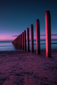 Wooden posts on beach against clear sky