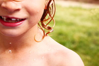 Close-up of wet shirtless smiling boy in back yard