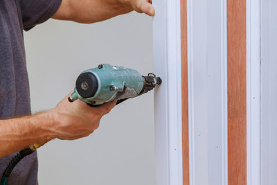 Close-up midsection of man using nail gun on wood