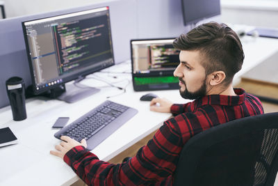 Side view of man using laptop at table