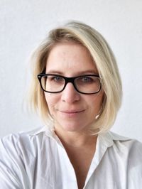 Portrait of smiling woman wearing eyeglasses against wall