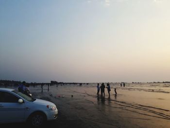 People on beach against sky during sunset