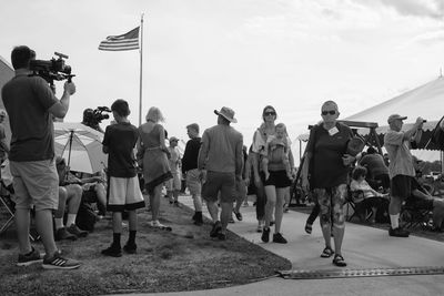 Group of people photographing at beach against sky