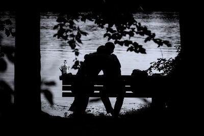 Silhouette people sitting on table by sea