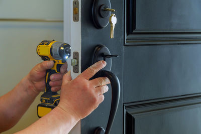 Cropped hand of man drilling door with drill machine