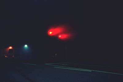 Illuminated red car against sky at night