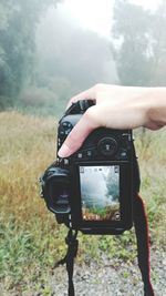 Man photographing camera on field against sky