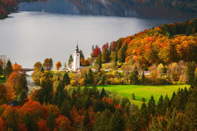 Scenic view of lake by buildings against trees during autumn