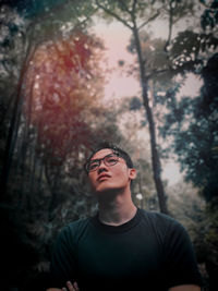 Portrait of young man standing against trees