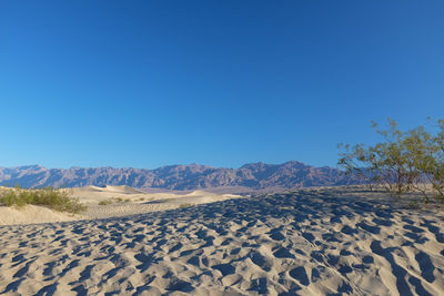 Scenic view of desert against clear blue sky