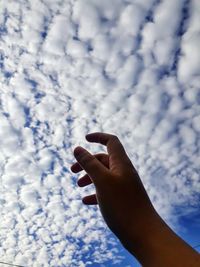 Low section of person holding hands against sky