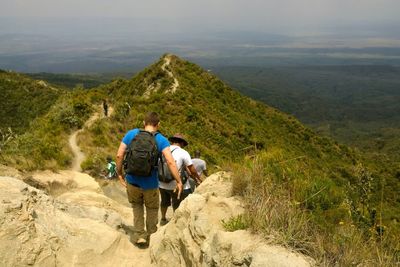 Rear view of men walking on mountain hiking trail at mount longonot, rift valley, kenya 