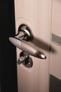 Close up, stylish new metal doorknob on modern interior door. shiny silver doorknob on a light door