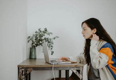 Young woman using laptop while sitting on table