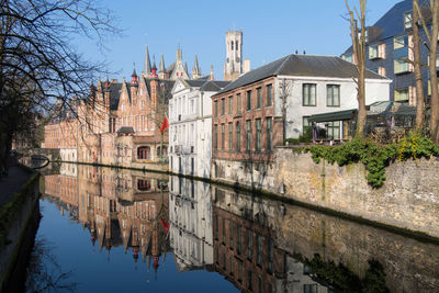 Buildings by river against sky