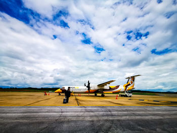 People at airport runway against sky