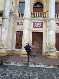 Full length of woman standing on footpath against building