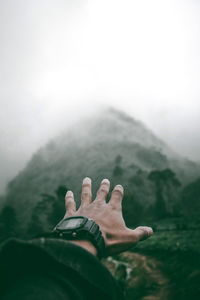 Cropped hand of man against mountain