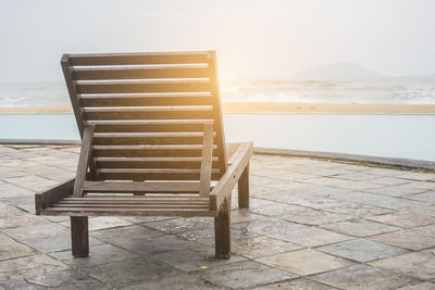 Chair on beach against sky during sunset