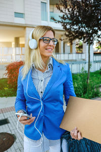 Smiling young woman wearing sunglasses standing against tree