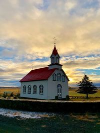 Church by building against sky during sunset