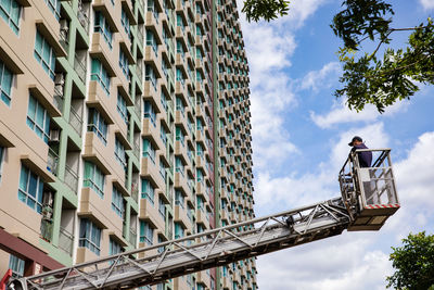 Low angle view of man working on building against sky