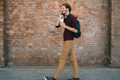 Full length of young man standing against brick wall