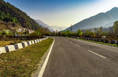 Tarmac road leading to the misty mountain valley with blue sky at morning from flat angle