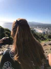 Rear view of woman looking at cityscape against clear sky