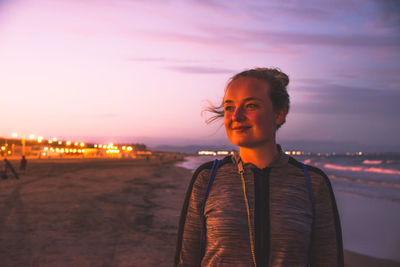 Young woman standing at beach during sunset