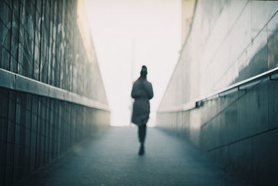 Rear view of man walking on footpath against building