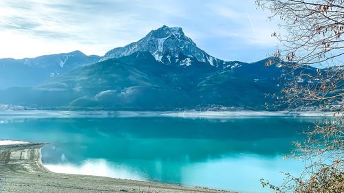 Scenic view of lake by snowcapped mountains against sky