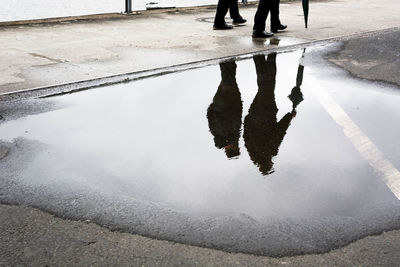 Low section of man walking on wet street