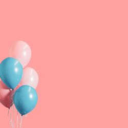 Multi colored balloons against pink background