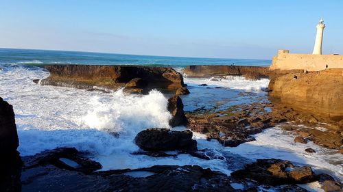 Rock formations on shore against sky