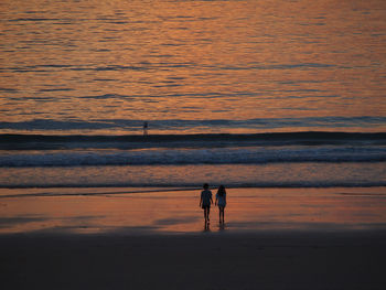 Silhouette woman walking at beach during sunset