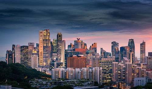 Modern buildings in city against sky during sunset