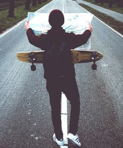 Full length of boy skateboarding on road
