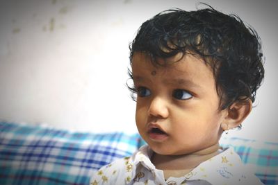 Close-up of cute baby boy on bed at home