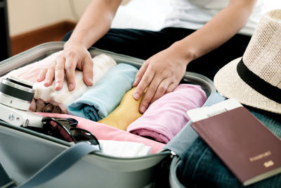 Midsection of woman packing clothes in suitcase