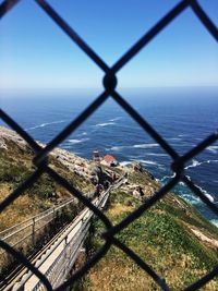 Scenic view of sea seen through chainlink fence