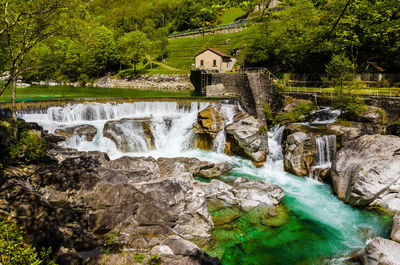 Waterfall by house against trees