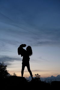 Silhouette woman standing against sky during sunset